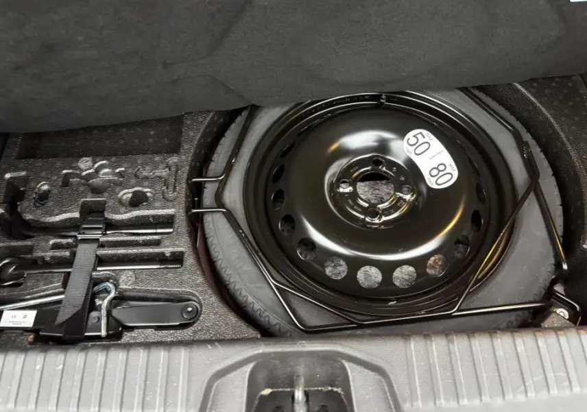 Coffre ouvert montrant la roue de secours et les outils de dépannage du Renault Clio V rouge flamme.