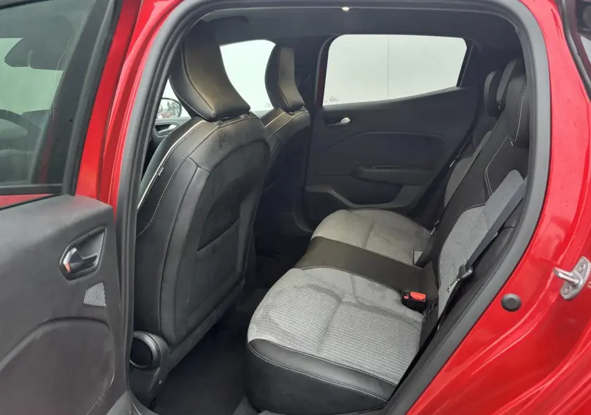 Vue intérieure arrière côté gauche d'une Renault Clio rouge flamme avec sièges arrière gris et noirs.