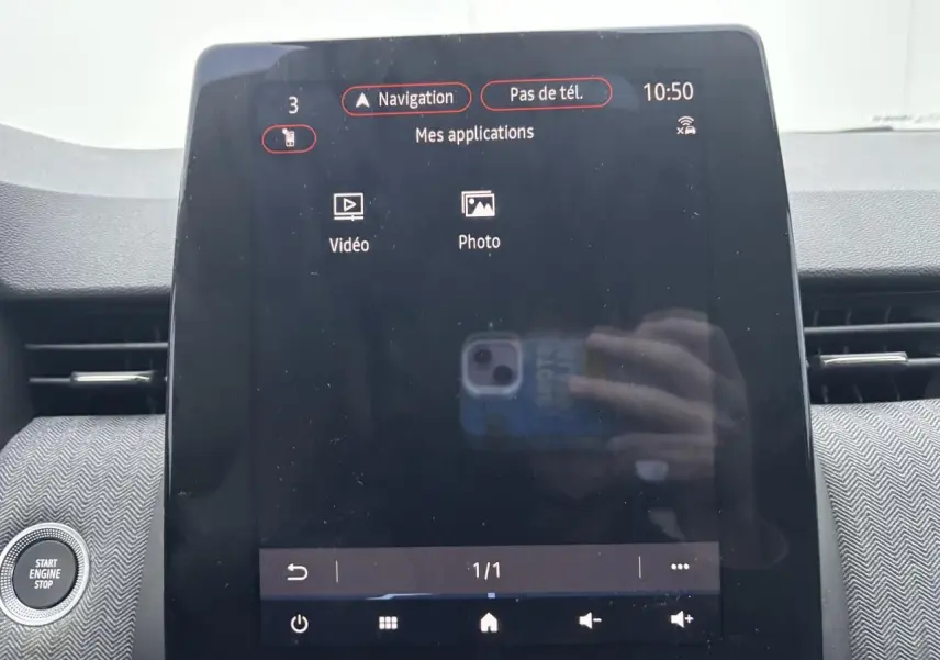 Vue rapprochée de l'écran tactile central du tableau de bord de la Renault Clio rouge flamme, affichant le menu navigation.