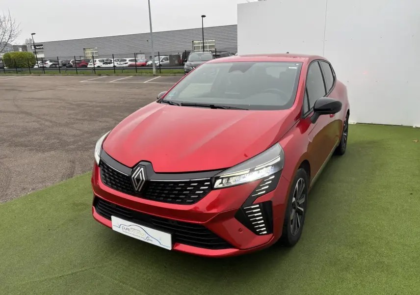 Renault Clio V hybride rouge flamme vue 3/4 avant droit, avec signature lumineuse LED distinctive et jantes alliage.