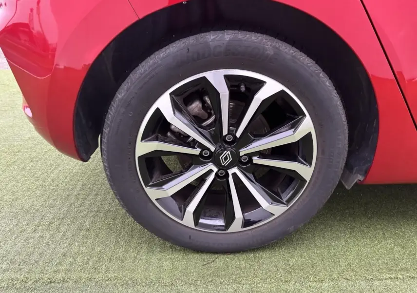 Gros plan sur la roue avant droite avec jante alliage noire et argentée de la Renault Clio rouge flamme.