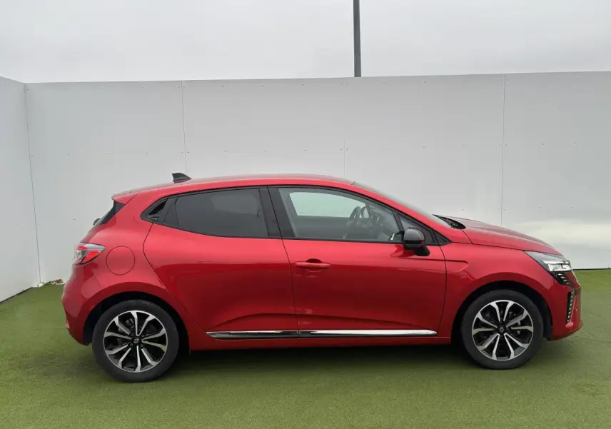 Profil droit d'une Renault Clio 2025 rouge flamme métal avec jantes alliage et vitres surteintées.