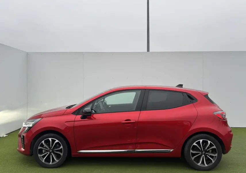 Profil côté gauche de la Renault Clio V rouge flamme métal avec jantes alliage et vitres surteintées.