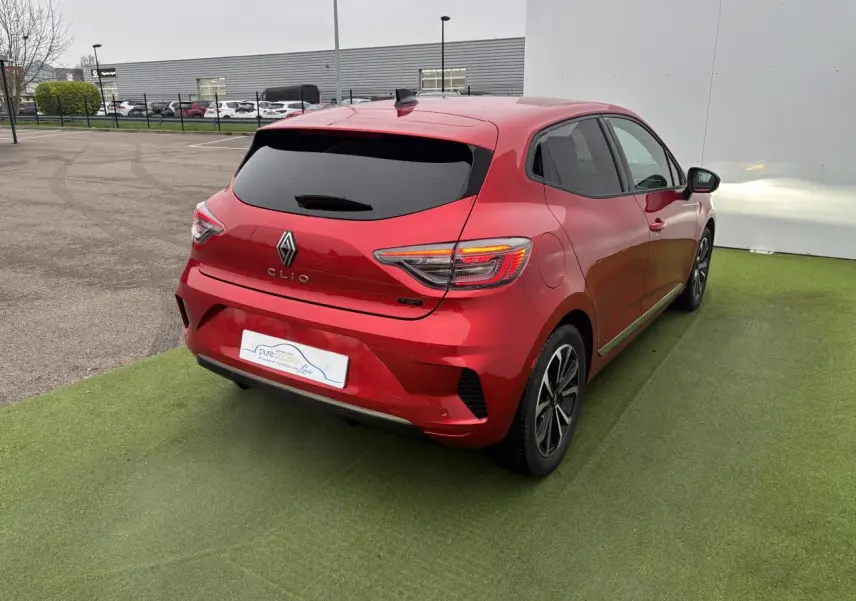 Renault Clio V rouge flamme métal vue 3/4 arrière droit, feux arrière LED et jantes alliage 16 pouces visibles.