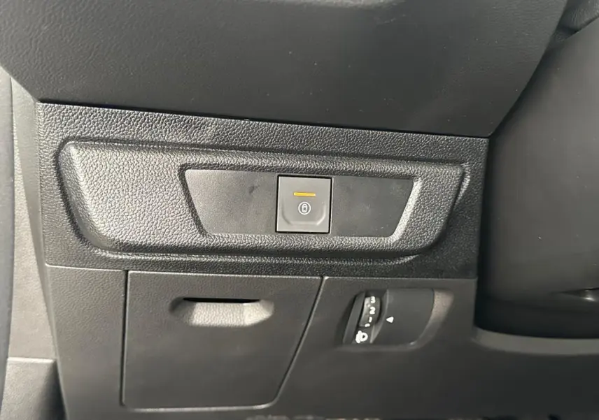 Détail du tableau de bord côté gauche de la Dacia Sandero blanche 2024, avec bouton de fermeture centralisée éclairé.