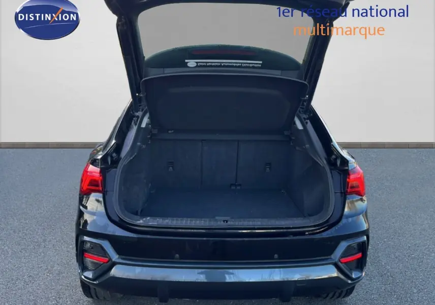 Vue arrière d’un Audi Q3 Sportback noir mythic avec coffre ouvert, mettant en valeur l’espace de chargement vide.