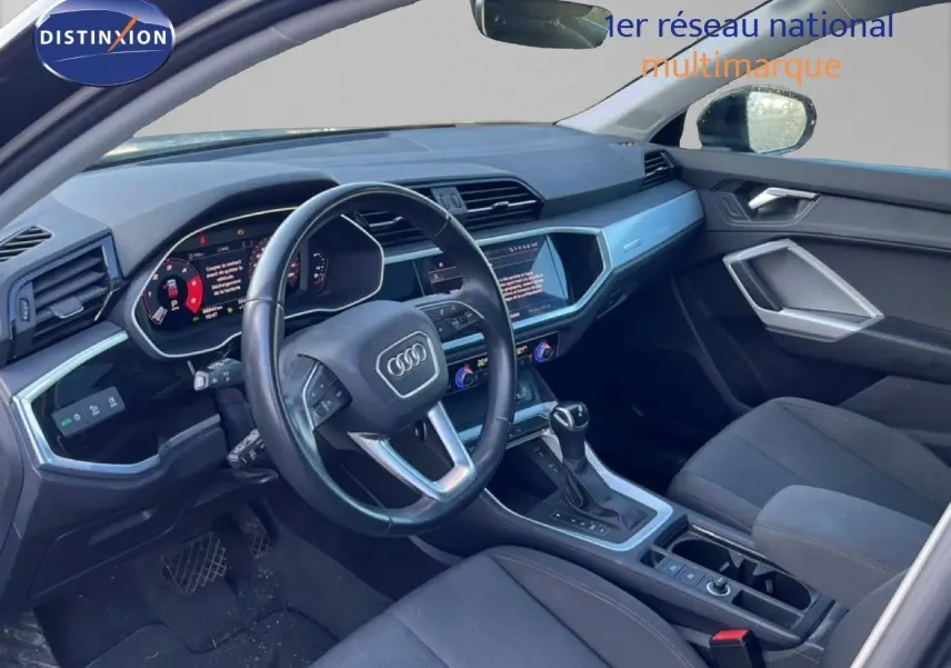 Intérieur de l'Audi Q3 Sportback 2022 vu côté conducteur, tableau de bord moderne et sièges noirs.
