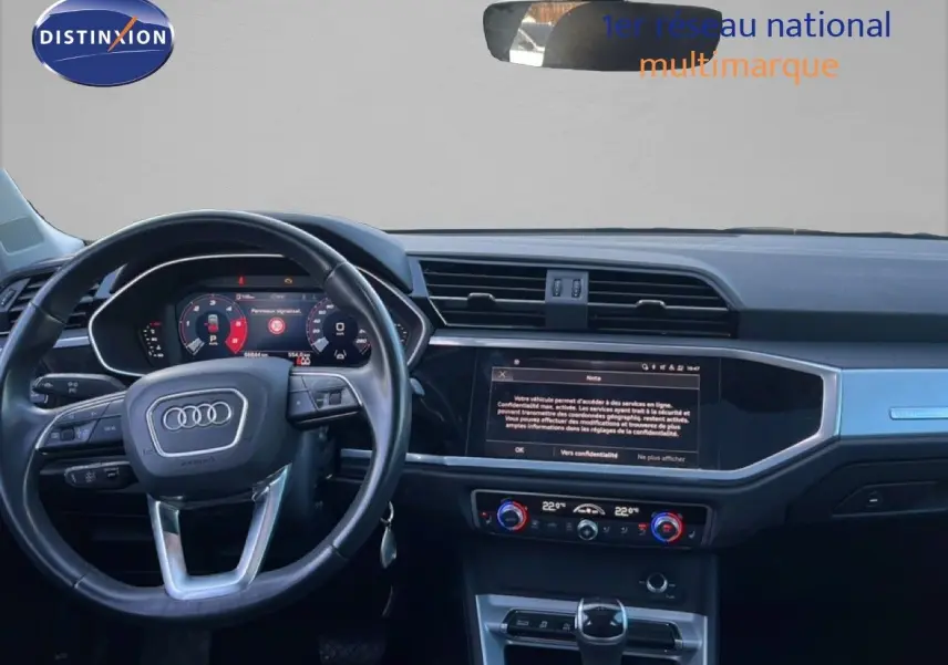 Vue intérieure de l'Audi Q3 Sportback 2022, tableau de bord et volant noir avec écran tactile central allumé.
