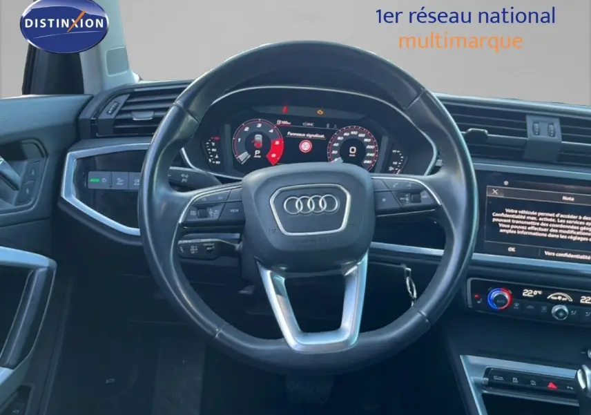Vue intérieure centrée sur le volant Audi noir avec tableau de bord numérique et écran tactile du Q3 Sportback 2022.
