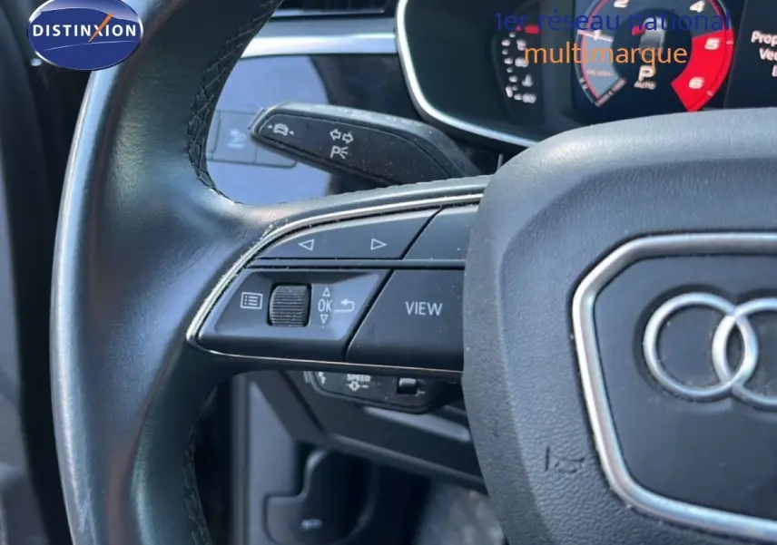 Gros plan sur le volant noir de l’Audi Q3 Sportback 2022 avec commandes multifonctions et tableau de bord numérique.