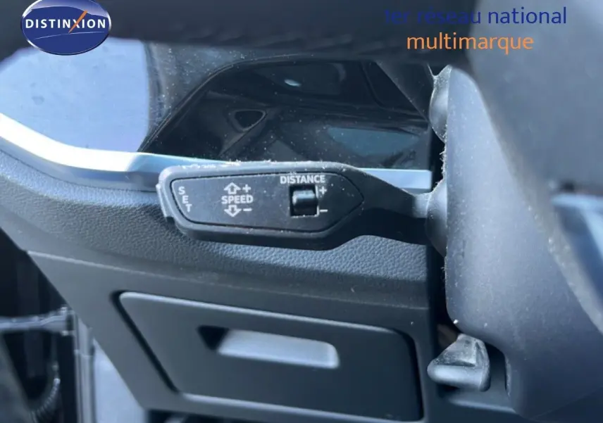 Gros plan sur la commande de régulateur de vitesse à gauche du volant dans l’Audi Q3 Sportback noir mythic 2022.