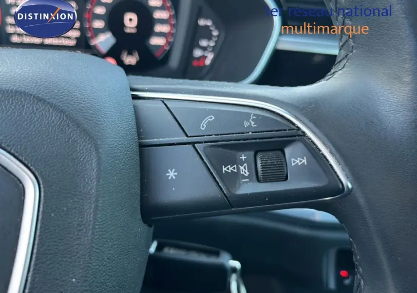Gros plan sur les commandes multifonctions noires à droite du volant d’un Audi Q3 Sportback noir mythic, tableau de bord flou en arrière-plan.