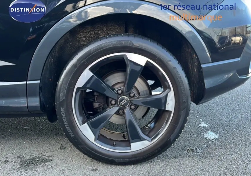 Gros plan sur la roue arrière droite d’un Audi Q3 Sportback noir mythic avec jante alliage bicolore.