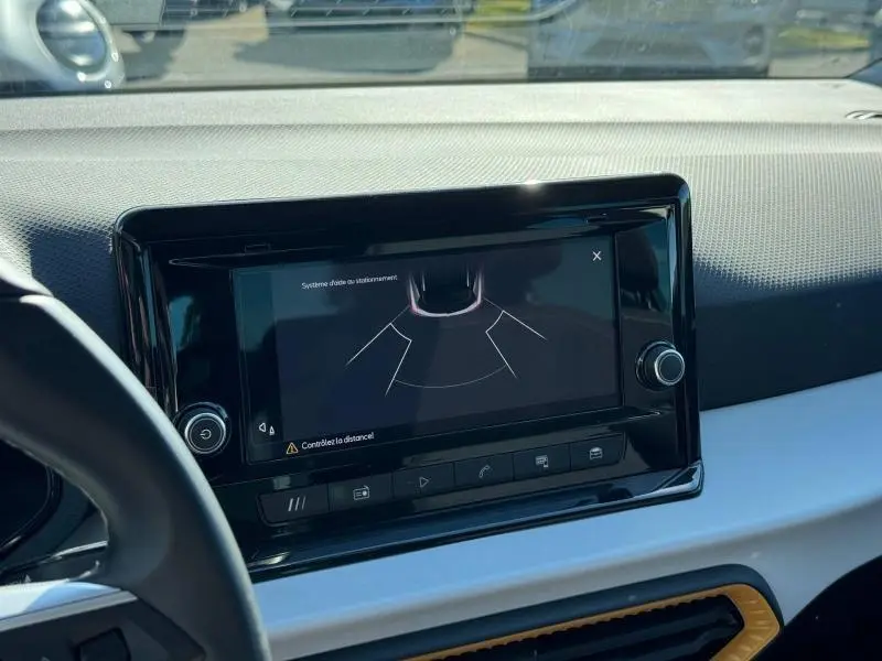 Écran tactile central vu de face dans l’habitacle clair d’un SEAT Arona 2025 avec tableau de bord noir et blanc.