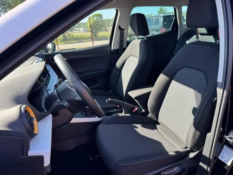 Intérieur avant de la SEAT Arona 2025 noir Minuit Métal, vue côté conducteur avec sièges tissu gris et volant cuir.