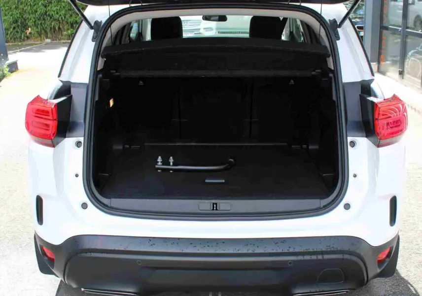 Vue arrière d’un Citroën C5 Aircross blanc 2020 avec coffre ouvert et attelage visible dans le coffre.