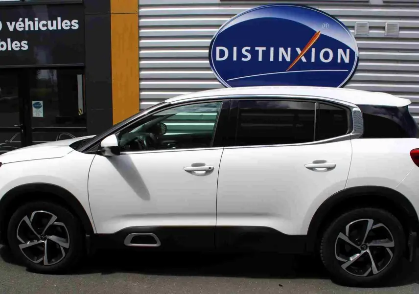 Vue de profil côté gauche d'un Citroën C5 Aircross blanc avec jantes alliage et attelage visible à l'arrière.