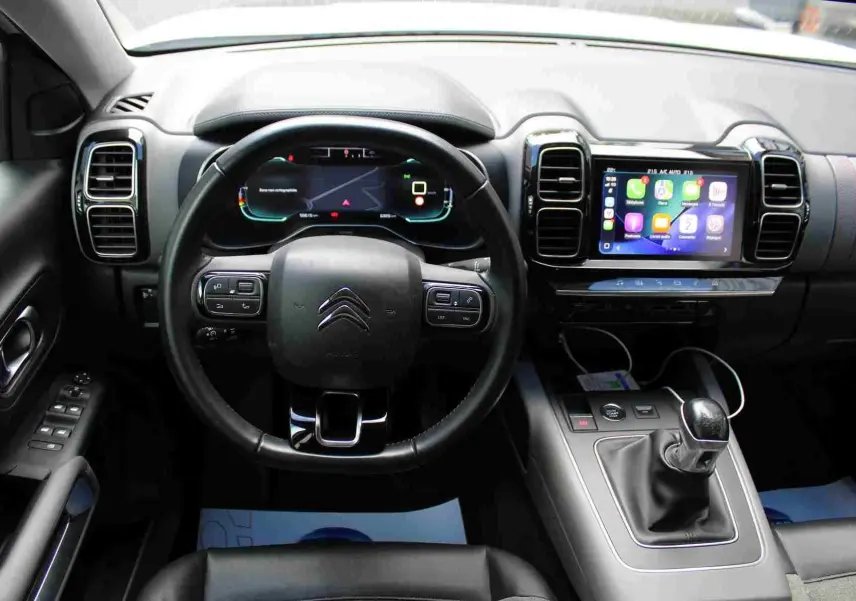 Vue intérieure centrée sur le tableau de bord et le volant du Citroën C5 Aircross avec écran tactile et levier de vitesse manuel.