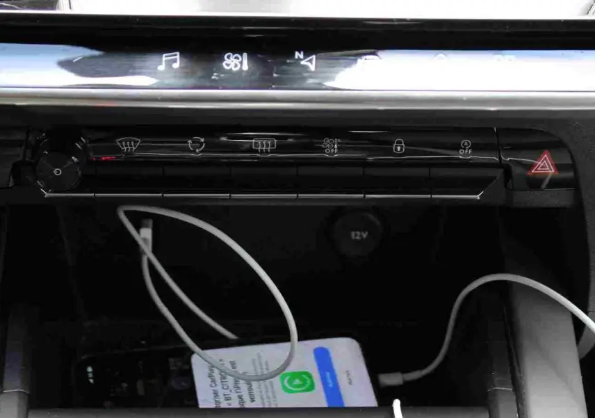 Gros plan sur la console centrale d'une Citroën C5 Aircross 2020, avec un smartphone blanc en charge via câble USB.