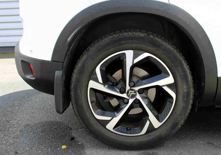 Gros plan sur la roue arrière droite du Citroën C5 Aircross blanc, avec jante alliage au design moderne bicolore.