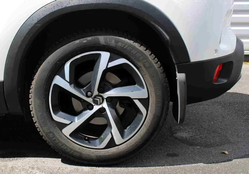 Gros plan sur la roue arrière droite d’un Citroën C5 Aircross blanc, avec jante alliage et pare-boue visible.