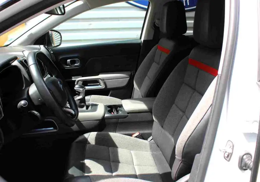 Vue intérieure côté conducteur du Citroën C5 Aircross blanc 2020, sièges tissu gris avec bande rouge et console centrale.