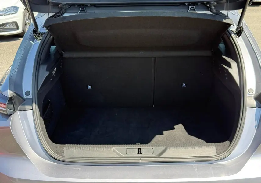 Coffre ouvert vu de l'arrière d'une Peugeot 308 e-308 gris Artense, montrant l'espace de rangement vide.