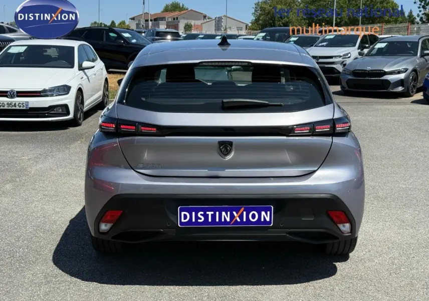 Vue arrière d'une Peugeot e-308 gris Artense 2025 avec feux LED et logo lion distinctif sur parking.
