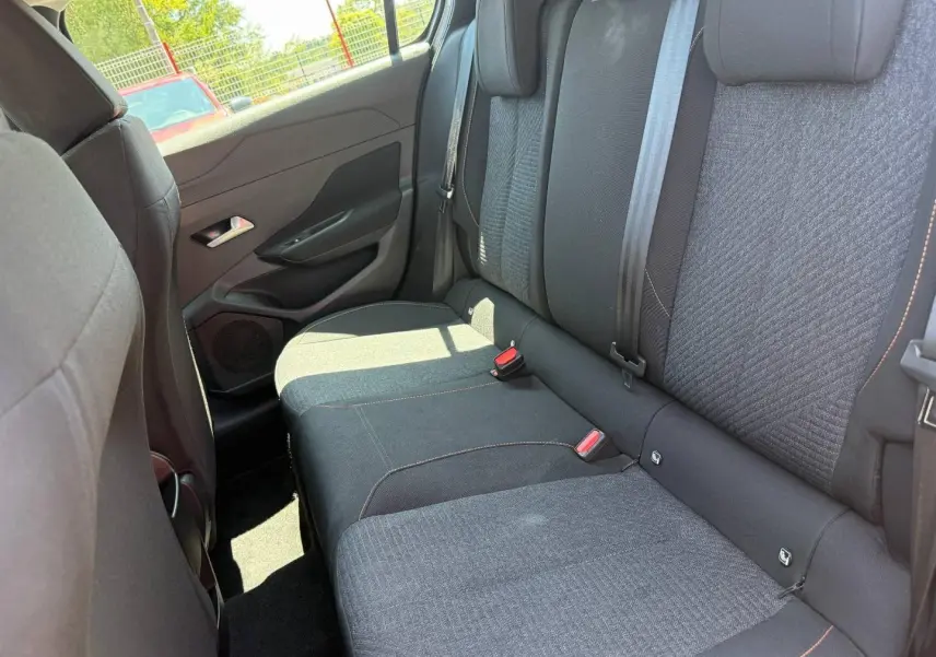 Vue intérieure côté gauche sur la banquette arrière tissu gris avec surpiqûres orange du Peugeot e-308 2025.