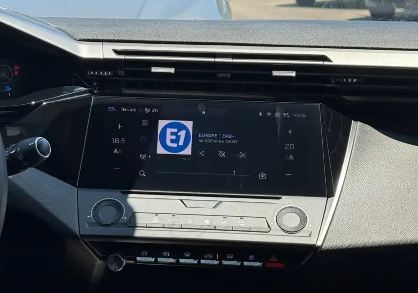Vue rapprochée de la console centrale de la Peugeot e-308 2025 gris Artense, avec écran tactile et commandes climatisation.