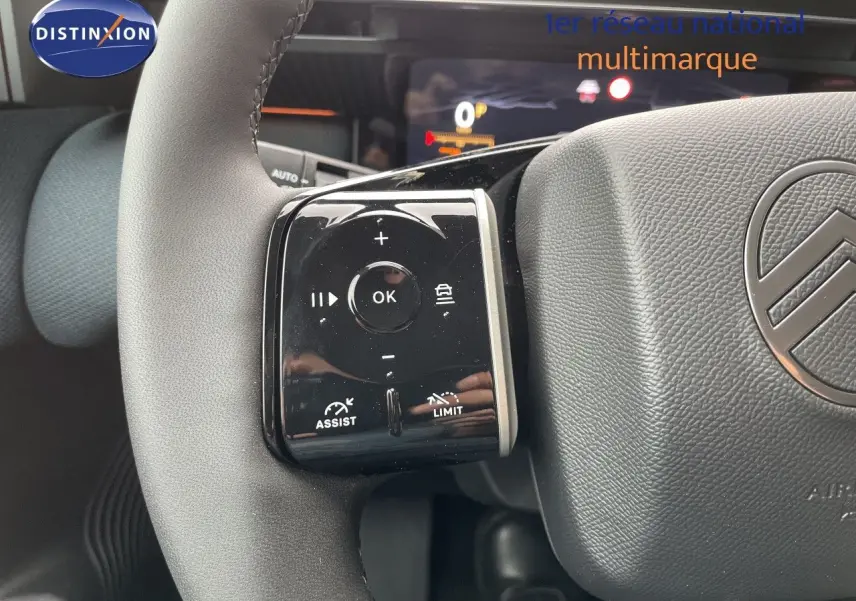 Gros plan sur le volant gris d’un Citroën C5 Aircross Hybrid 2026, avec commandes multifonctions et logo Citroën visible.