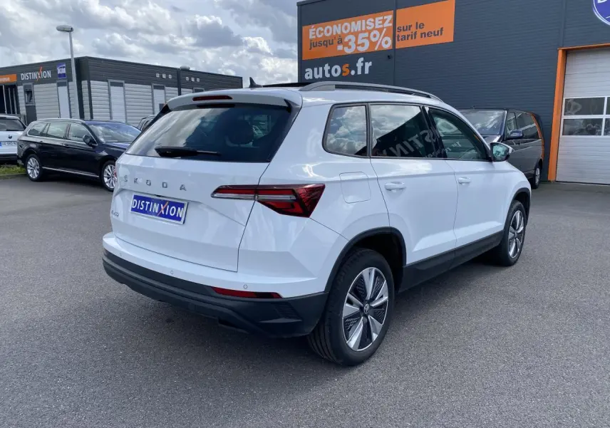 Vue 3/4 arrière droite d'un Skoda Karoq blanc Moon métallisé avec jantes alliage et toit ouvrant panoramique.