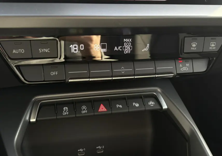 Gros plan sur la console centrale de l’Audi A3 Berline 30 TFSI 2024, affichage digital de la climatisation à 18°C.
