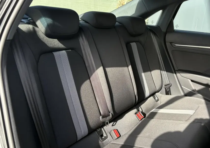 Vue intérieure montrant la banquette arrière noire avec bandes grises de l'Audi A3 Berline 2024, côté droit.