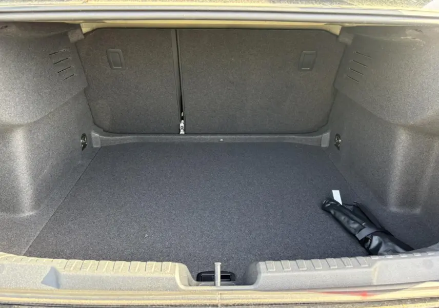 Coffre ouvert de l'Audi A3 Berline 2024 noir Mythe, montrant un espace de chargement propre et vide avec un objet noir roulé.