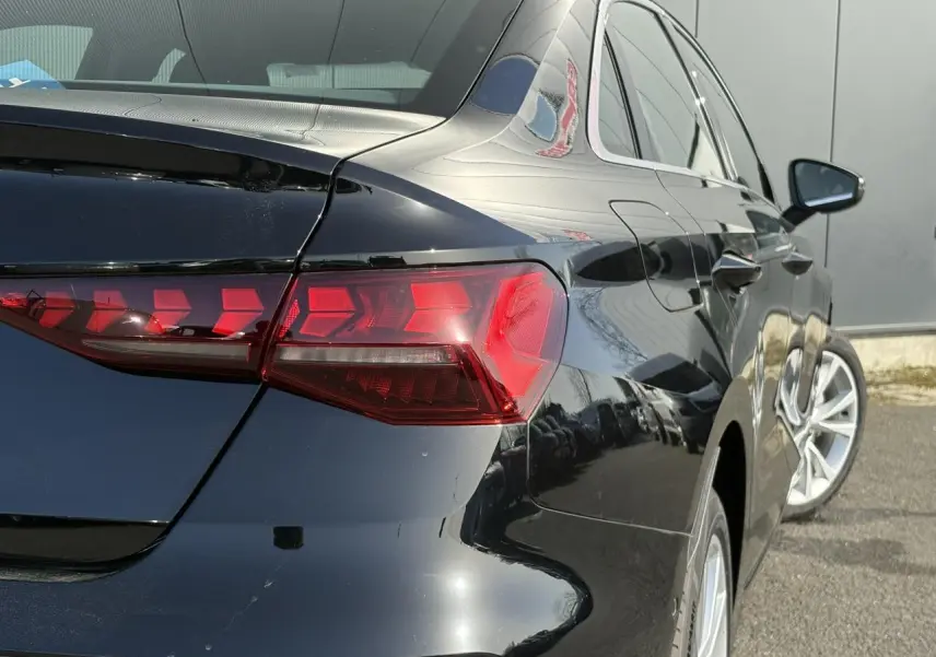 Vue 3/4 arrière droite de l'Audi A3 Berline 30 TFSI noir Mythe avec feux arrière LED distinctifs et jantes 17 pouces.