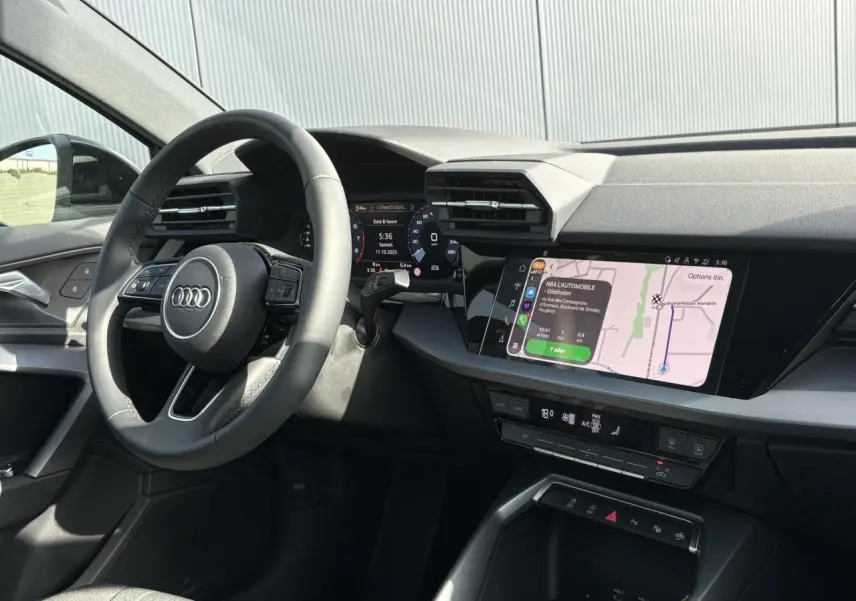 Vue intérieure côté conducteur de l'Audi A3 Berline 30 TFSI 2024, tableau de bord avec écran tactile et volant cuir noir.