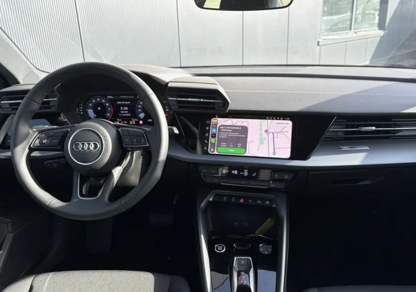 Vue intérieure avant de l'Audi A3 Berline 2024 noir Mythe, avec tableau de bord digital et écran central tactile.