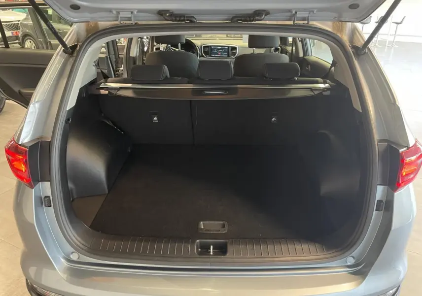 Coffre ouvert vu de l'arrière d'un KIA Sportage gris clair 2021 avec intérieur noir et tablette de coffre.