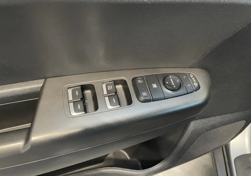 Vue rapprochée des commandes de lève-vitres et rétroviseurs sur la porte côté conducteur du KIA Sportage gris clair 2021.