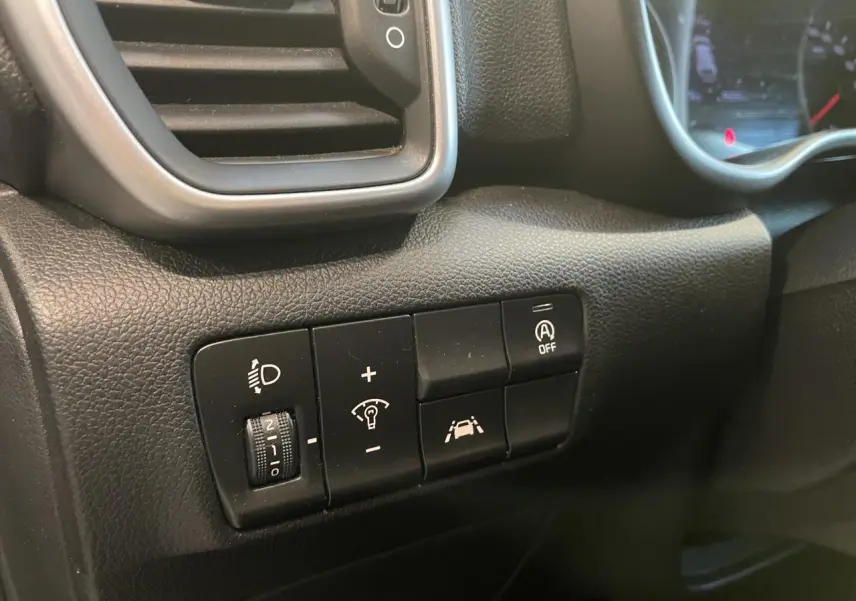 Gros plan sur les commandes noires du tableau de bord du Kia Sportage gris clair, côté gauche du conducteur.