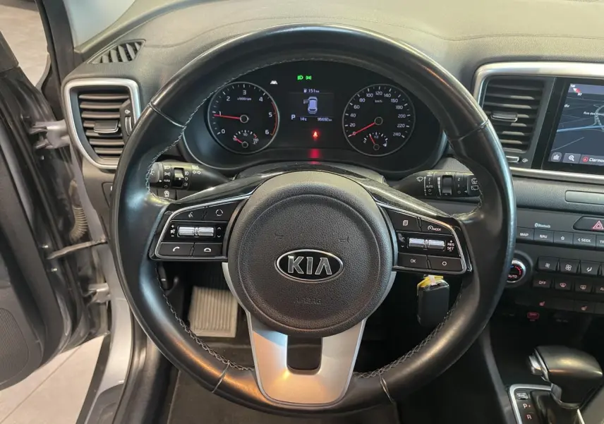 Vue intérieure centrée sur le volant noir du Kia Sportage 2021 avec tableau de bord et écran tactile visibles.