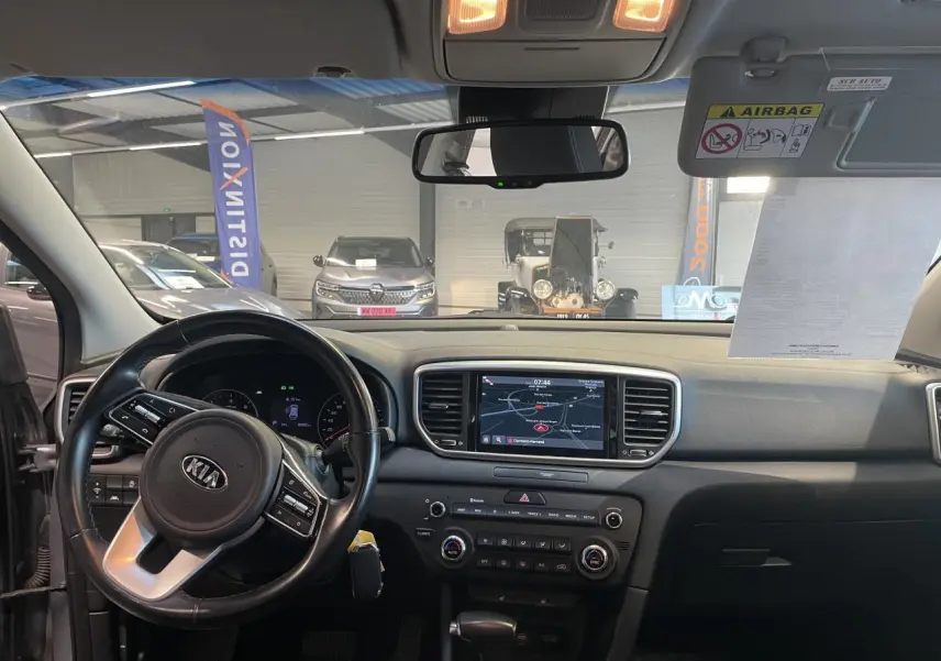 Vue intérieure avant du Kia Sportage 2021, tableau de bord noir avec écran tactile et volant multifonctions.