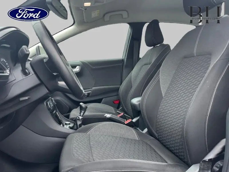 Intérieur avant du Ford Puma 2023, sièges tissu noir Kasbah avec surpiqûres blanches, volant et levier de vitesses visibles.