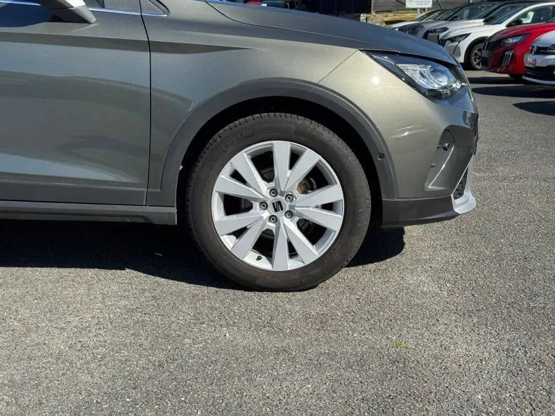 Gros plan sur la roue avant droite et partie latérale grise métallisée d'une SEAT Arona 2025.