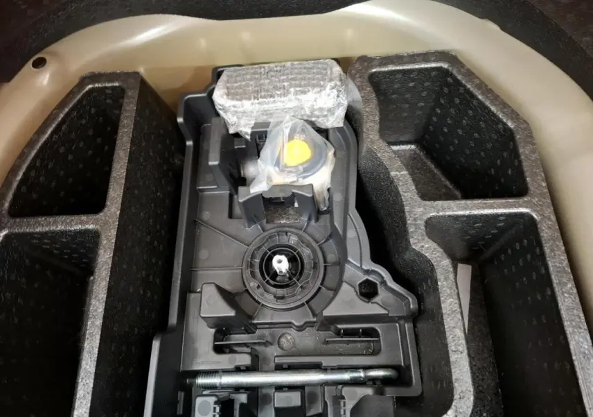 Coffre ouvert montrant le rangement pour kit de dépannage pneumatique de la Peugeot 208 gris Artense.