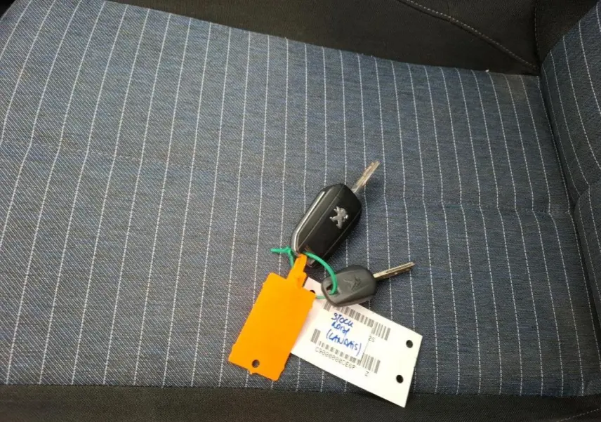 Clé Peugeot posée sur siège tissu bleu à rayures grises, intérieur d’une Peugeot 208 1.2i 2021.