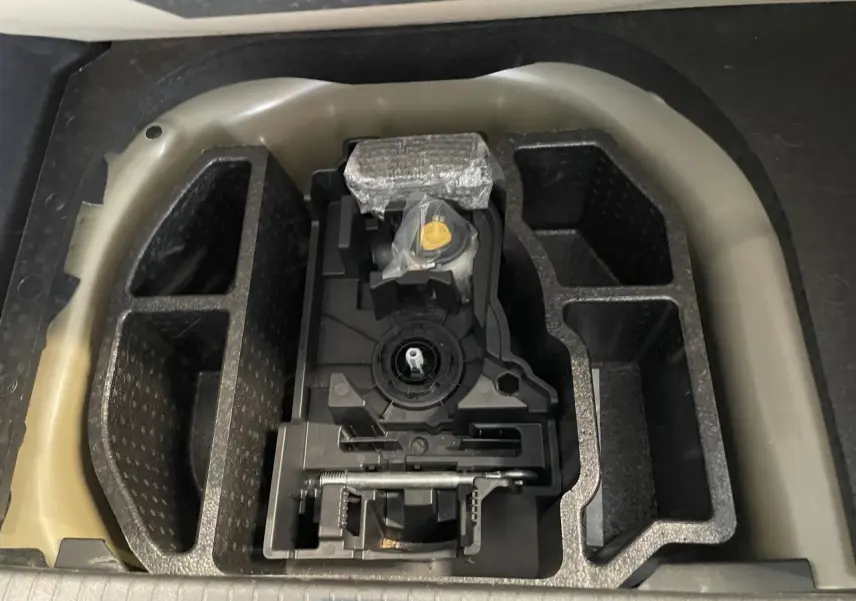 Compartiment de rangement sous coffre de la Peugeot 208 gris Artense, avec kit de dépannage pneumatique rangé.