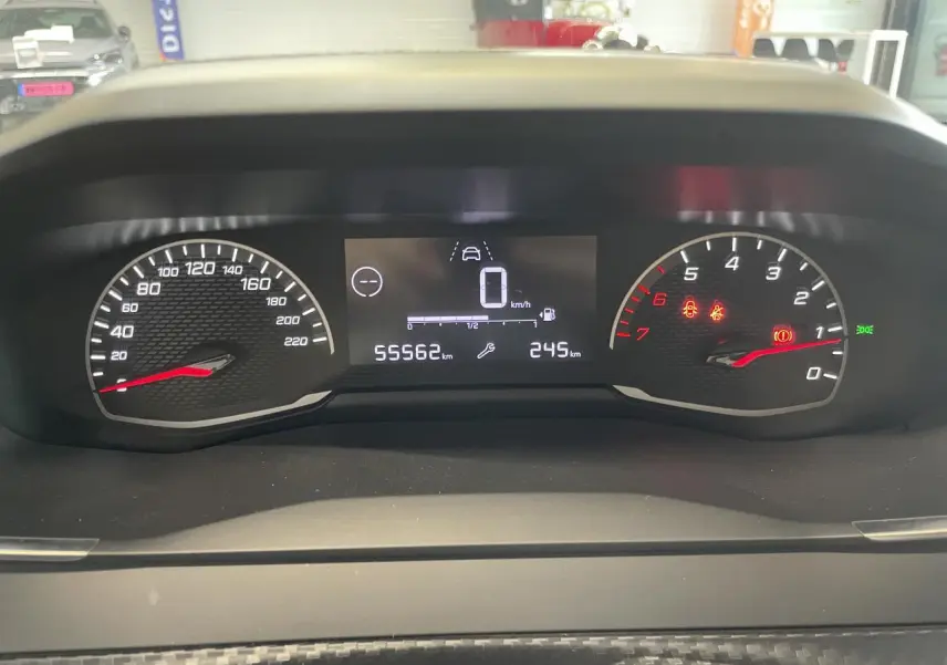 Vue rapprochée du tableau de bord numérique et analogique de la Peugeot 208 gris Artense, affichant 55562 km.