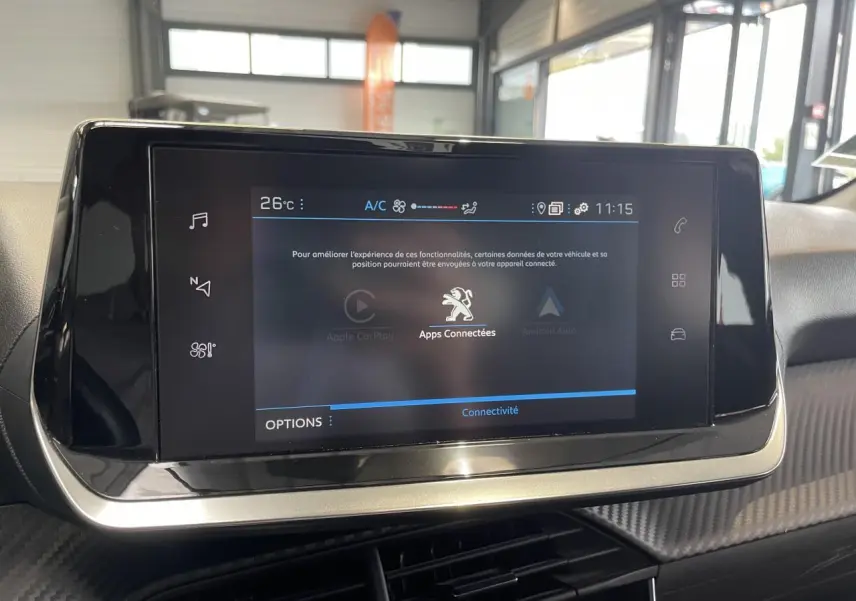 Écran tactile central du tableau de bord Peugeot 208 2021, avec interface connectée et finition carbone.